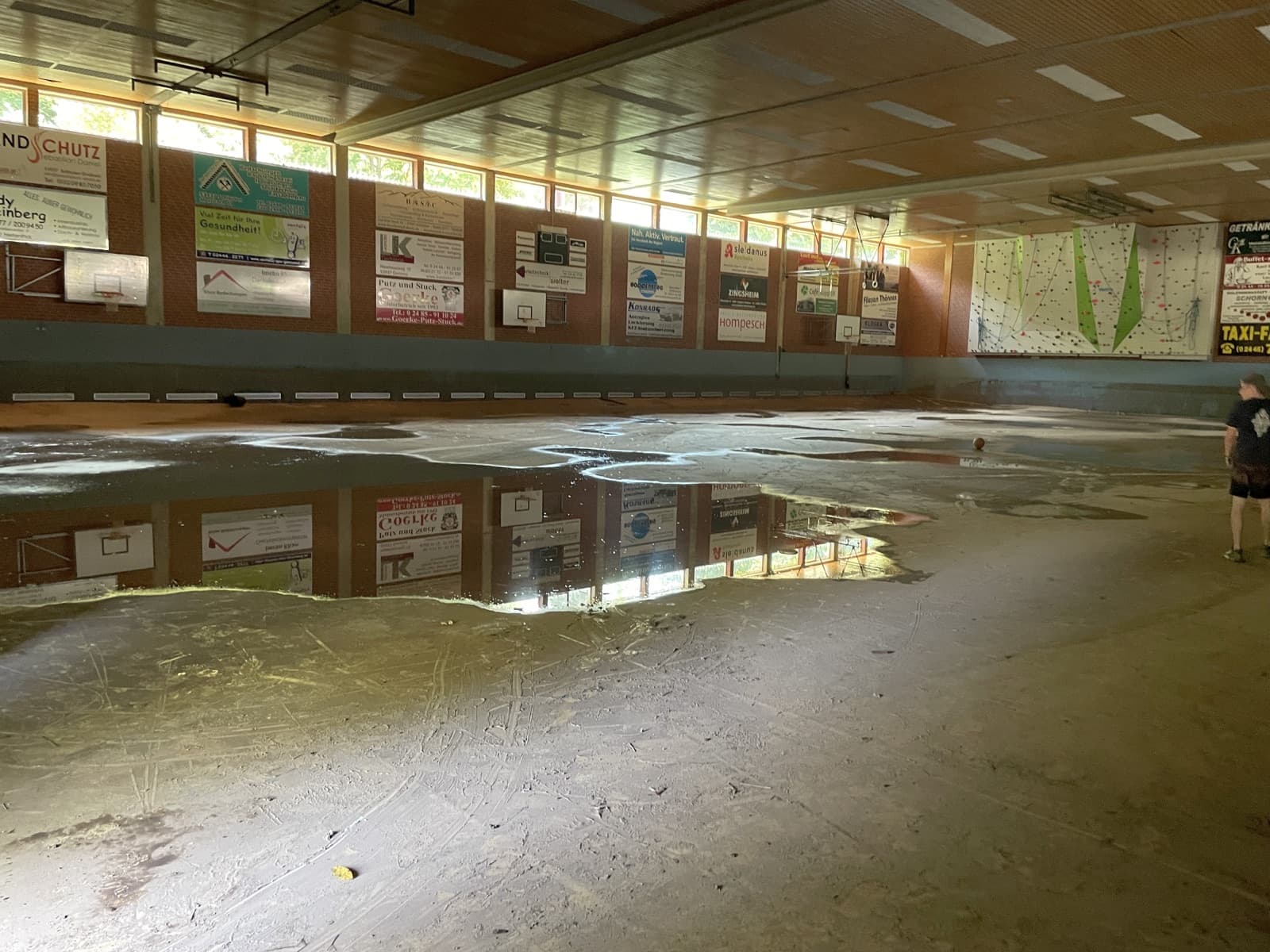 Sporthalle nach dem Hochwasser: stehendes Wasser und Schlammfilm auf dem Hallenboden