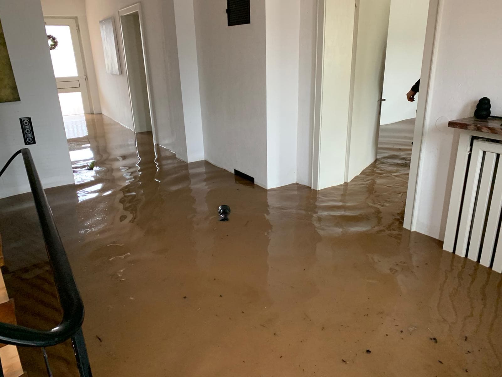 Erdgeschossflur einer Wohnung, flächig mit schlammigem Hochwasser bedeckt bis an die Türzargen