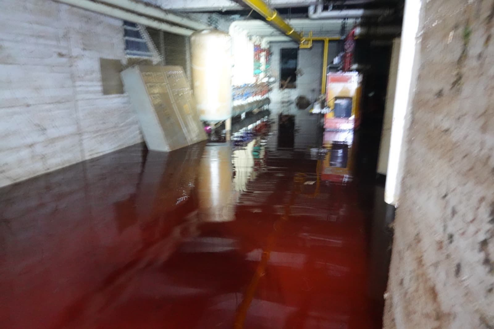 Kellergang, in dem trübes Hochwasser hoch steht und Regale und Einbauten spiegelt