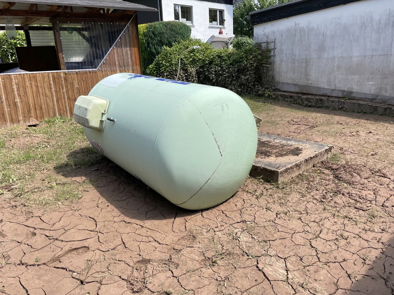 Losgerissener Tank, der auf einer aufgerissenen Schlammschicht in einem Garten liegt